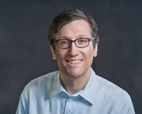 Rabbi Tzemah Yoreh, smiling, wearing glasses and a light blue shirt